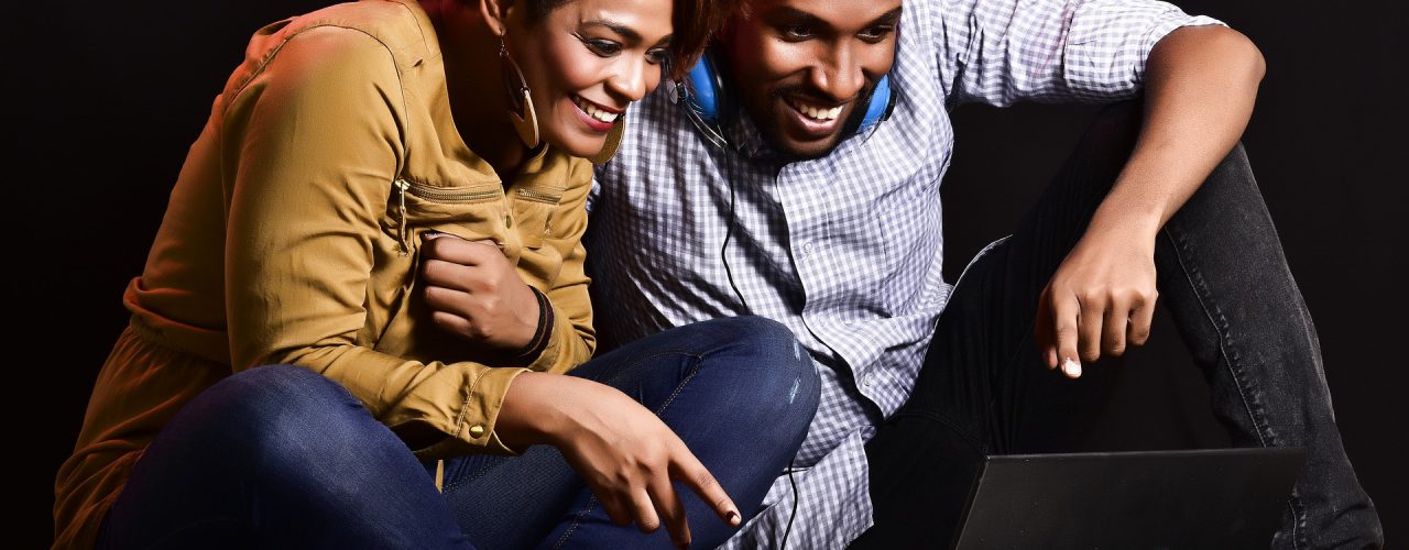 woman and man sitting in front of computer smiling