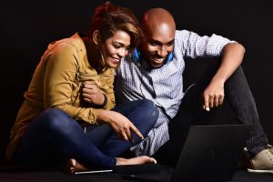 woman and man sitting in front of computer smiling