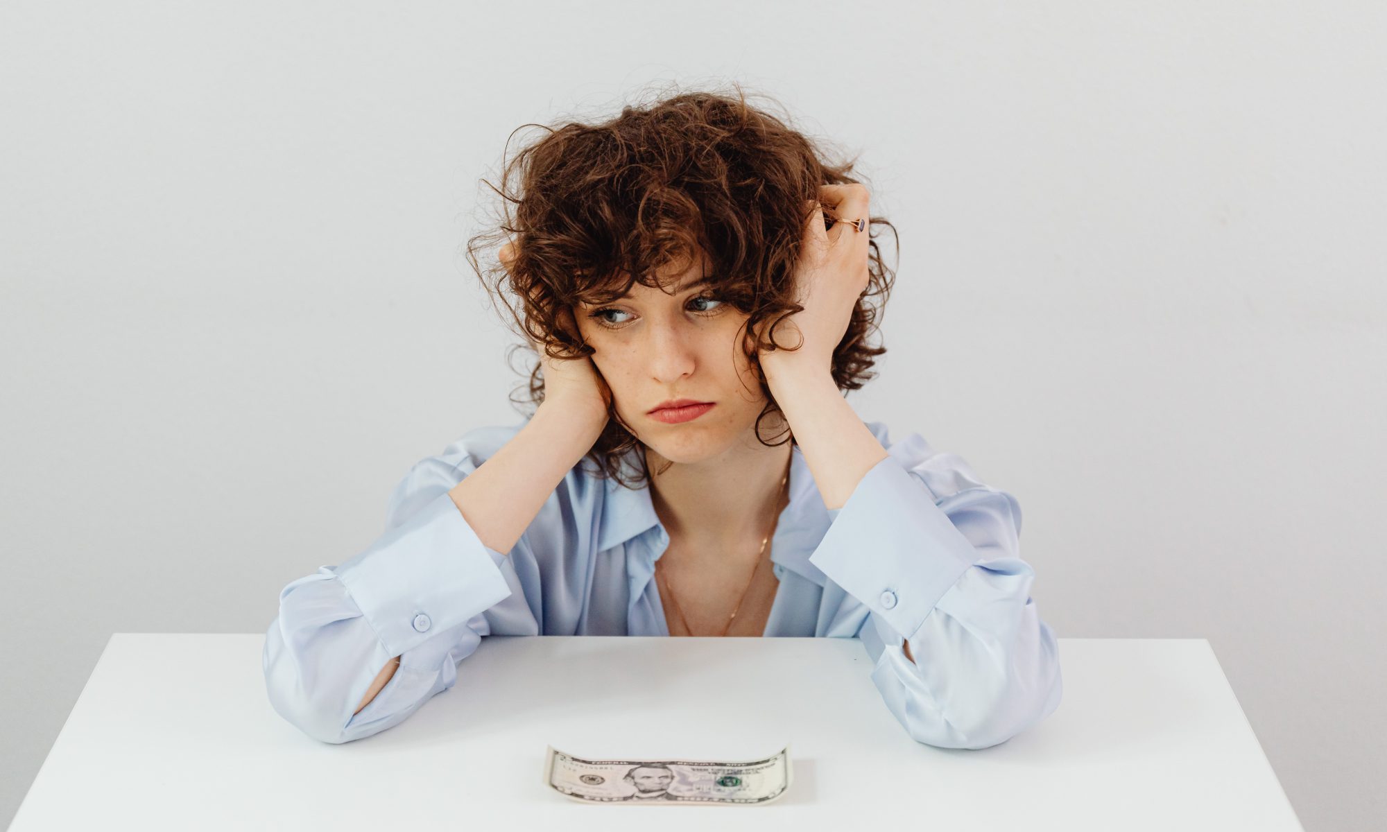 A stressed woman with a dollar infront of her.