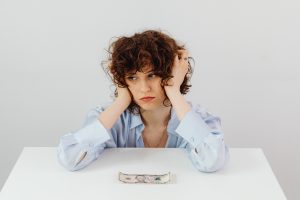 A stressed woman with a dollar infront of her.