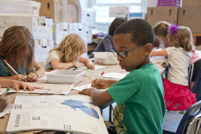 Children doing school work on a table.