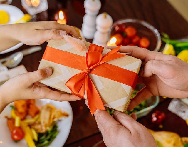 A person handing another person a small box with a bow.