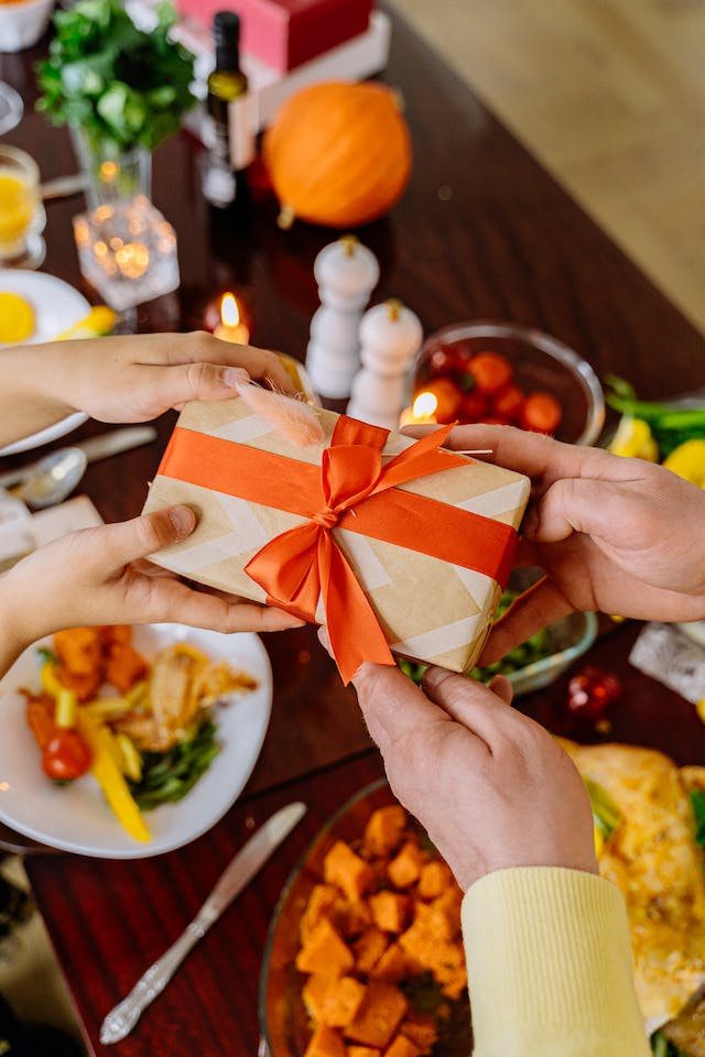 A person handing another person a small box with a bow.