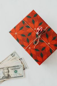 Some cash next to a christmas gift box.