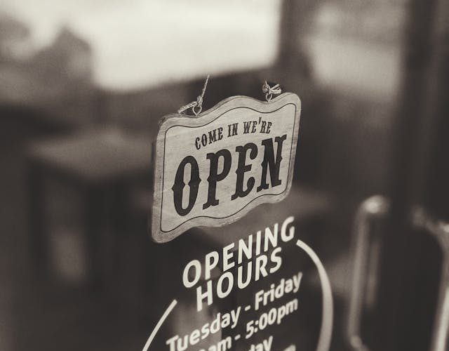 An sign on a business window. The sign says the business is open.