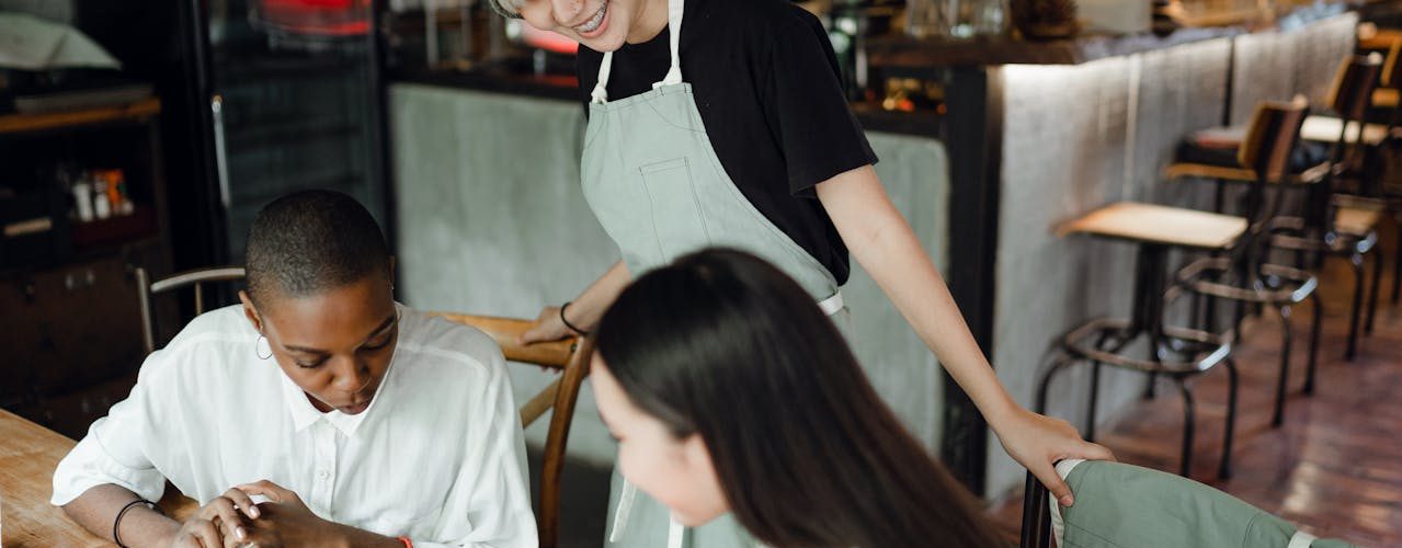 A waitress talking to 2 customers.