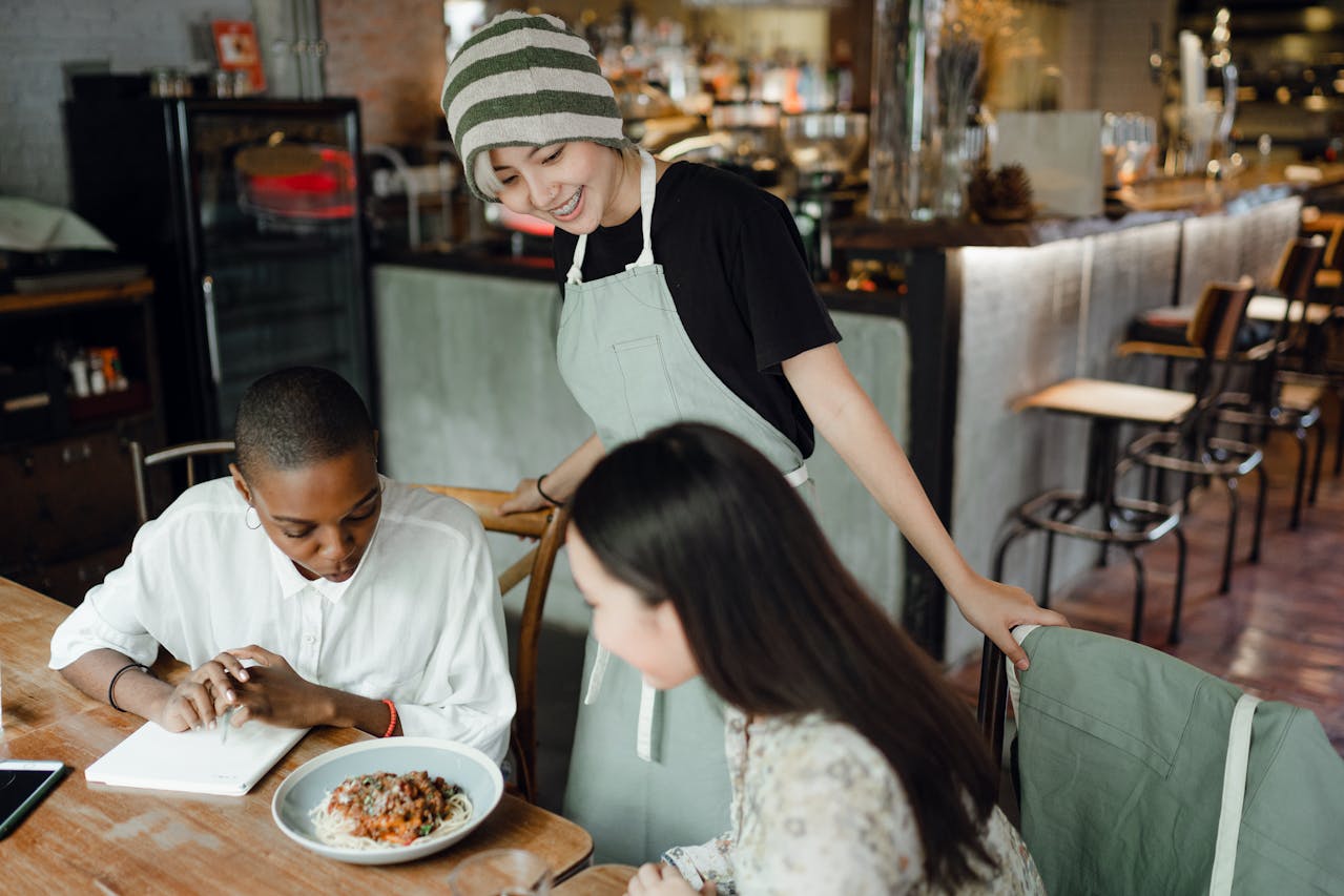 A waitress talking to 2 customers.