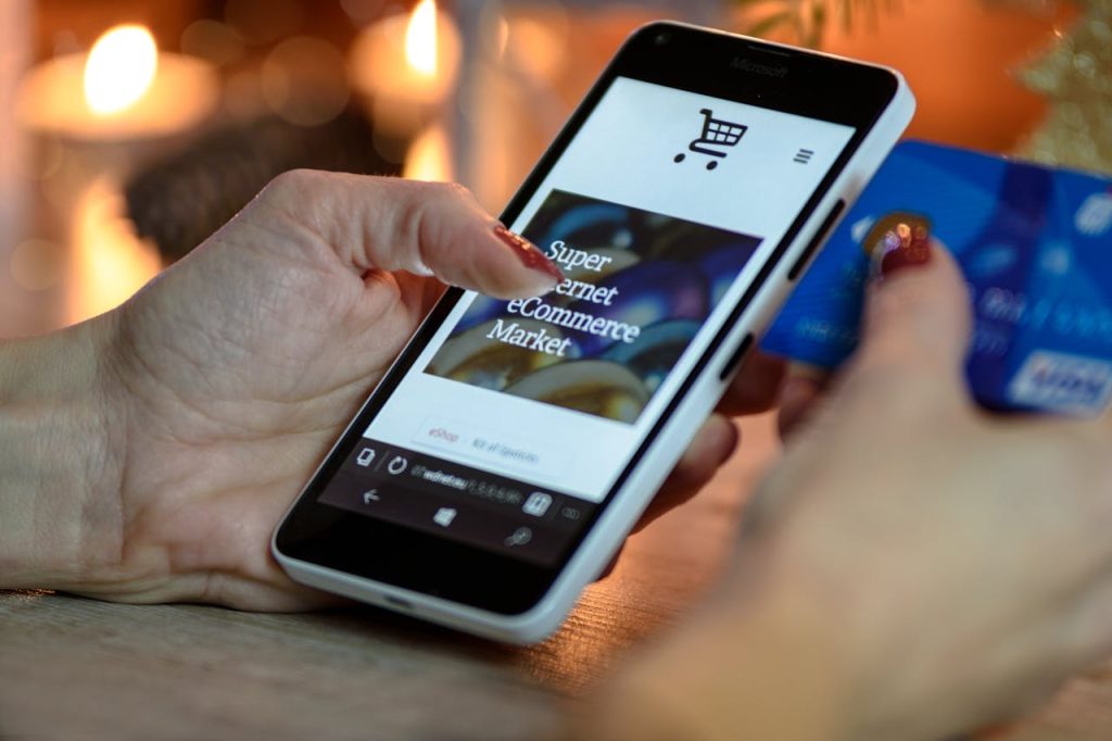 A person holds their smartphone and their credit card.