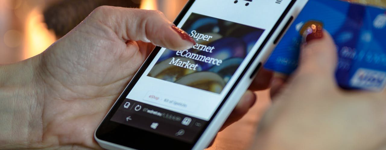 A person holds their smartphone and their credit card.